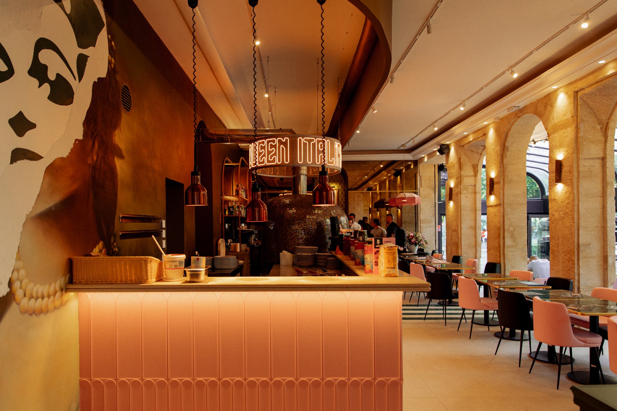 Italian Queen Avignon – pink counter, neon ring above the mosaic oven and stone arcades, photo Jon Filin