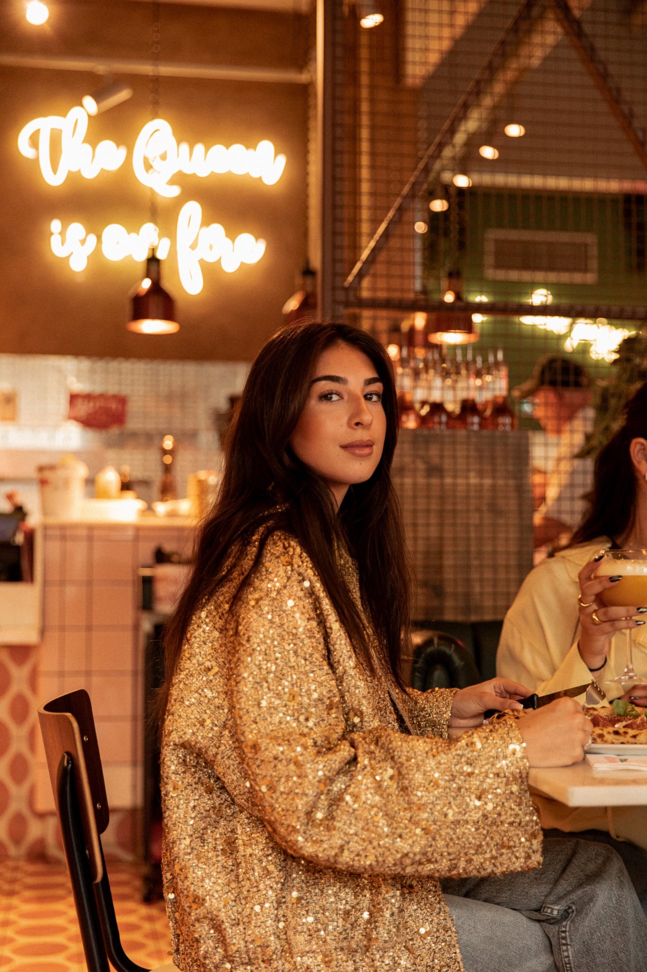 Italian Queen Val d’Europe – model in a gold sequin jacket under The Queen is on fire neon, photo Jon Filin